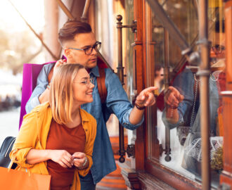Beautiful young couple enjoying in shopping together standing in front of shop window.